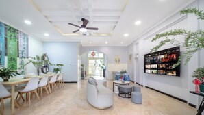 A spacious living area with a modern design, featuring a seating arrangement, a television mounted on the wall, and a ceiling fan. - Villa in the park (Guiyang)