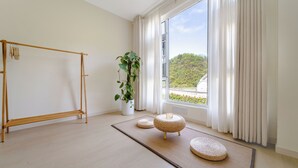 A room with a tatami mat, a wooden shelf, a potted plant, and a view of a hill through a large window. - Villa in the park (Guiyang)