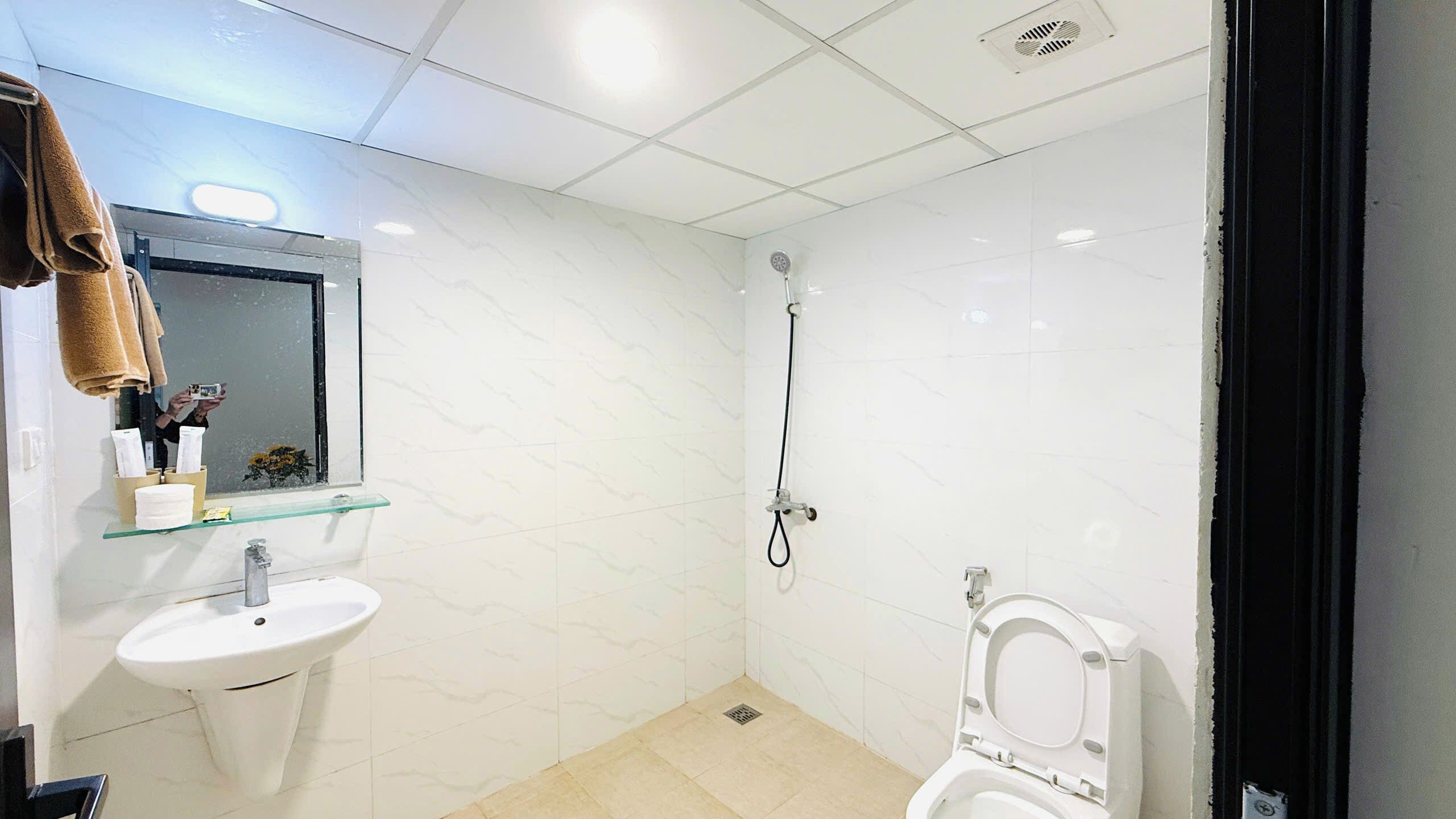Een badkamer met een wit wastafel, een glazen plank met toiletartikelen, een handdouche en een toilet.