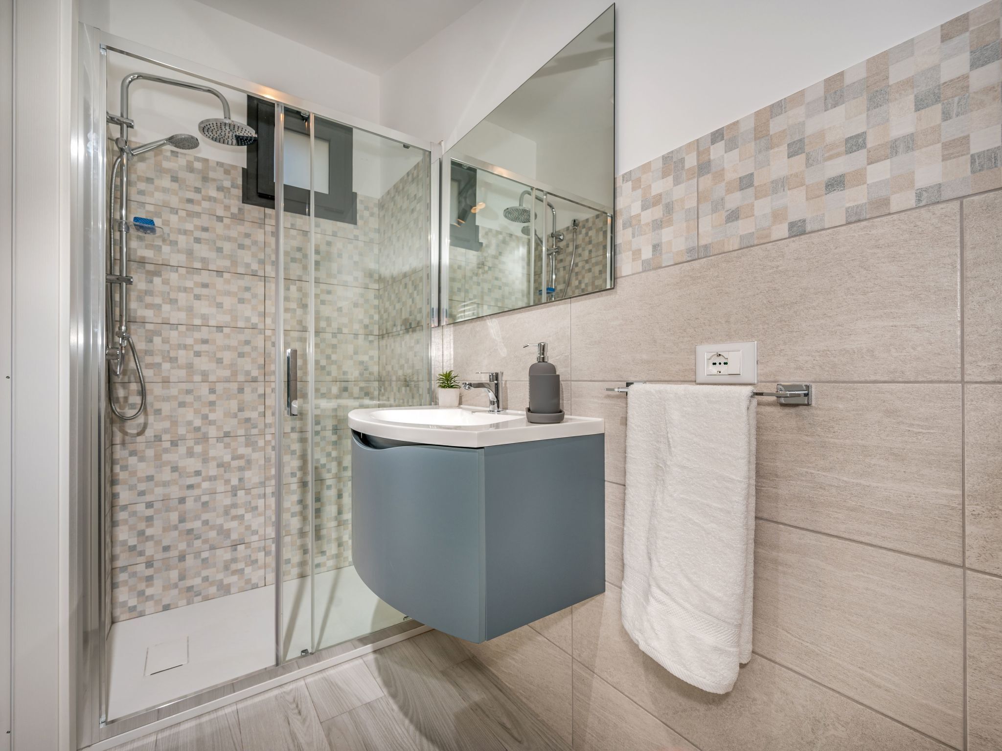 A modern bathroom with a glass-enclosed shower, a built-in sink, and a mirror above the vanity.