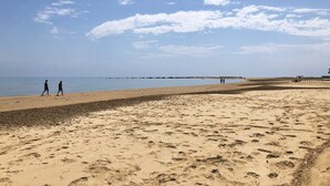 A wide sandy beach with footprints and a clear sky.