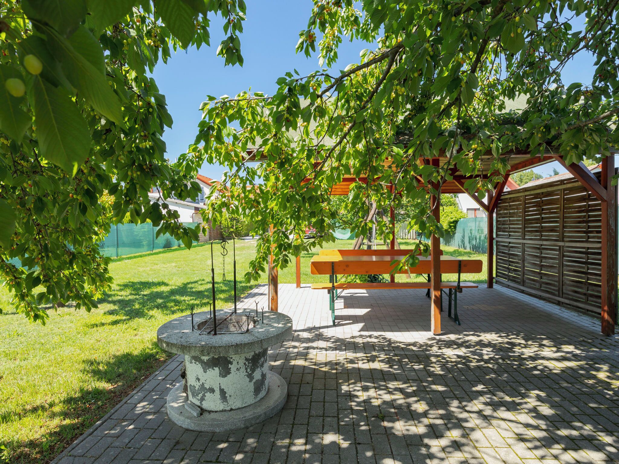 En park med en planteringslåda i betong, träbänkar och en pergola.