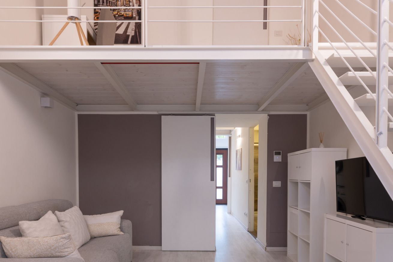 Ein modernes Interieur mit einer Couch, einem Fernseher und einer Treppe.