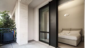 A modern bedroom with a large window, a bed, and a small bedside table. - Two-room apartment Cecchi 18 2p - Mirable PM (Milano)