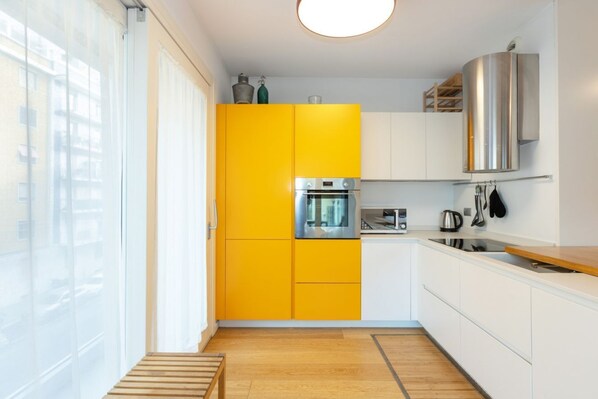 A modern kitchen with yellow cabinets, a stainless steel oven, and a wooden countertop.