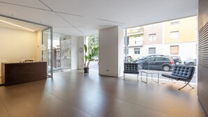 Un espace d’accueil moderne comprenant un comptoir de réception, des sièges et de grandes fenêtres donnant sur le parking et les bâtiments environnants.