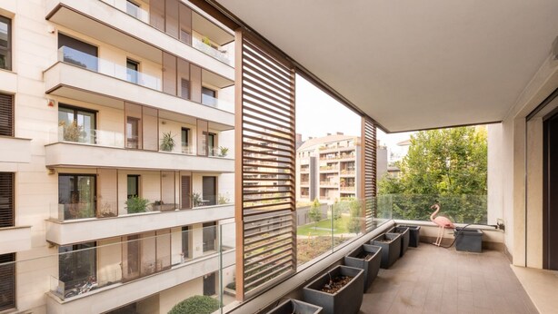 Un appartement moderne doté de plusieurs balcons, de grandes fenêtres et de plantes en pot.