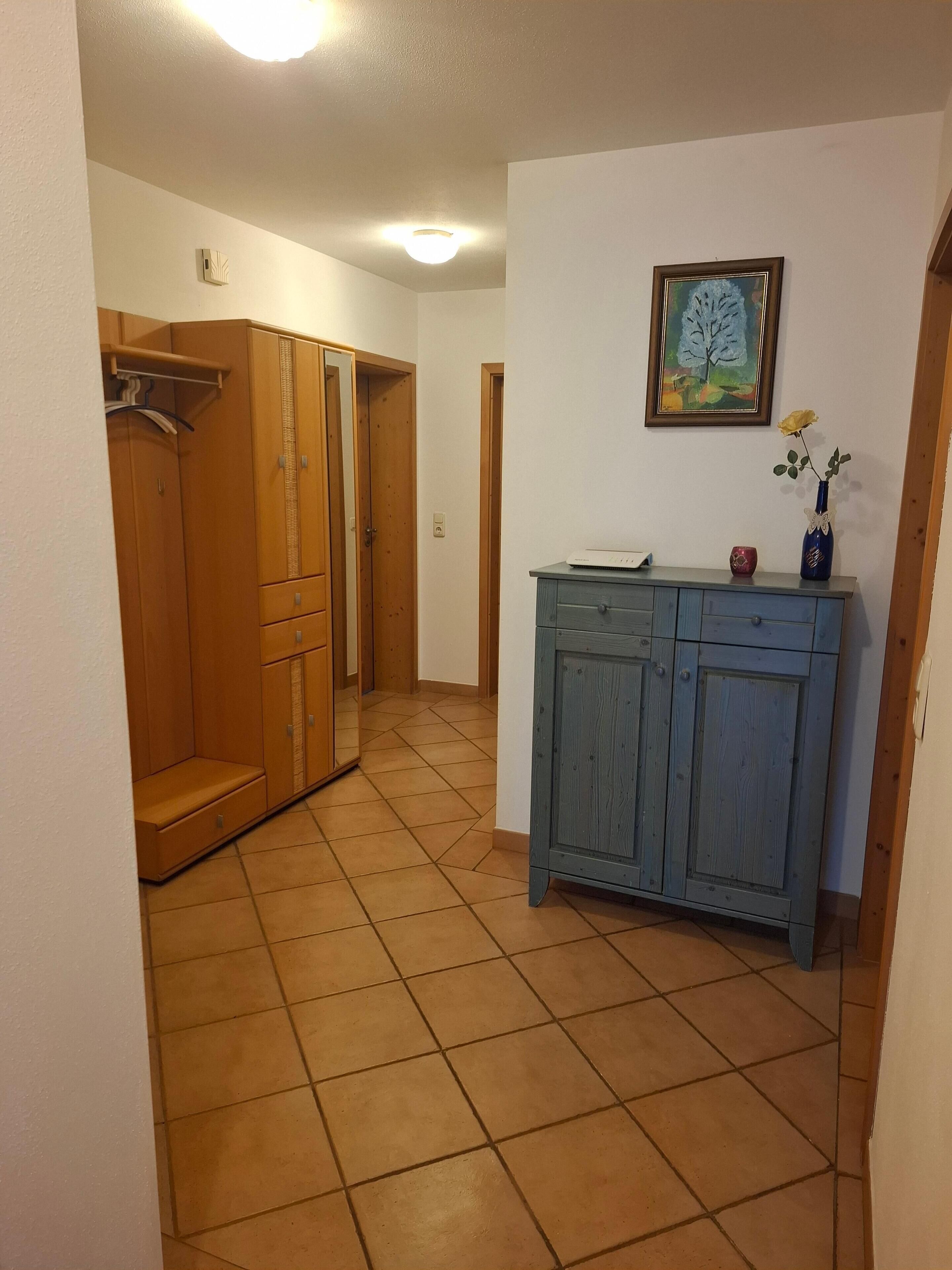 A hallway with a wooden wardrobe, a blue cabinet, and a framed painting on the wall.