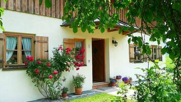 Ein traditionelles Haus mit Holzbalkon, einer Tür und Blumentöpfen.