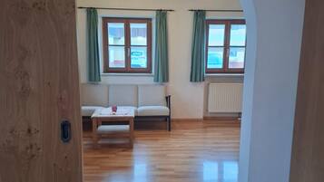 Ein Zimmer mit Holzboden, einer Couch, einem Tisch und einer Deckenleuchte.