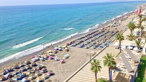 A beach with rows of sunbeds and umbrellas, a clear sky, and the ocean. - Casa Ascen by At Home Costa del Sol (Torrox)