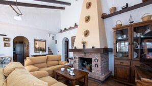 A spacious living room with a fireplace, beige sofas, wooden cabinets, and a tiled floor. - Casa Ascen by At Home Costa del Sol (Torrox)