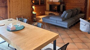 En mysig stuga med en inredning som inkluderar ett matbord i trä, en soffa och en öppen spis.