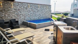 An outdoor patio with a stone wall, a hot tub, lounge chairs, and a built-in sink. - Between Mala and Asia Boulevard, Bujama Beach house in Moravia II! (Bujama, Asia)