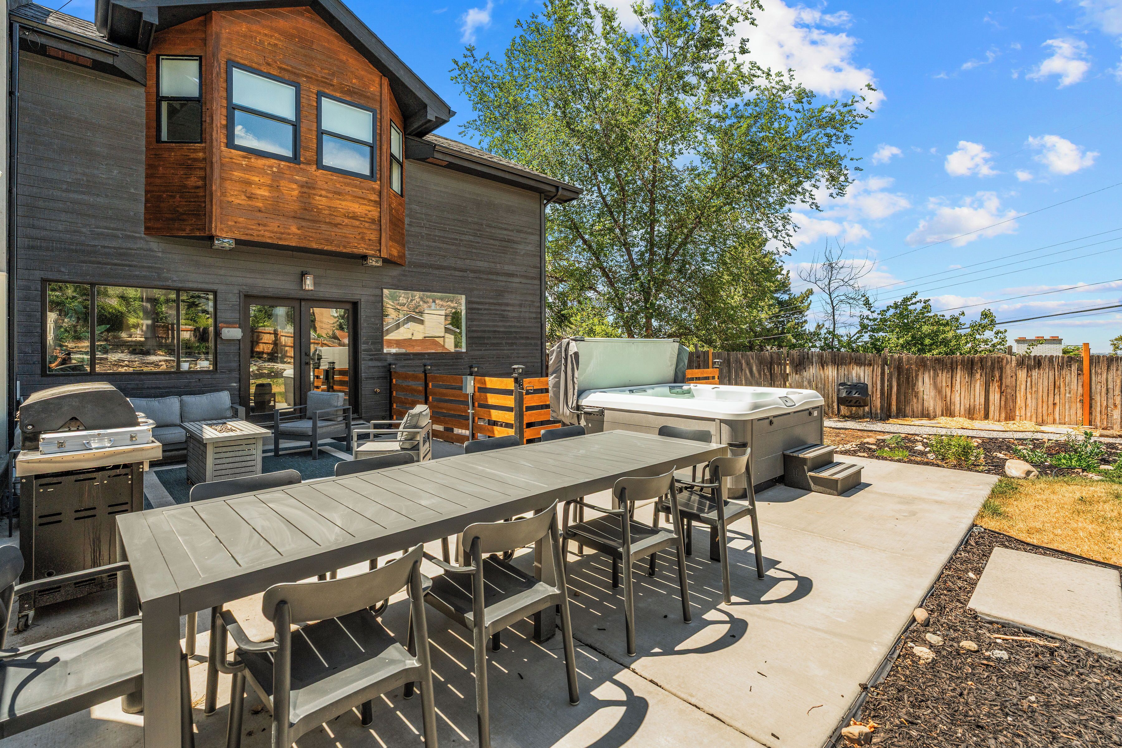 A modern house with a patio area featuring a barbecue, outdoor seating, and a hot tub.