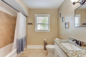 Ein Badezimmer mit Badewanne, Toilette, Waschbecken und Fenster.