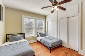 Ein Schlafzimmer mit zwei Einzelbetten, einem Deckenventilator und einem Fenster mit Jalousien.