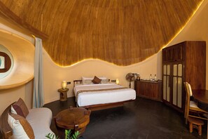 A bedroom with a large bed, a wooden ceiling, a wooden cabinet, and a small table. - Toroland Munnar  (Devikolam)