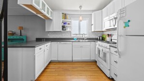 Una cocina moderna con gabinetes blancos, encimera de madera, horno integrado y refrigerador.