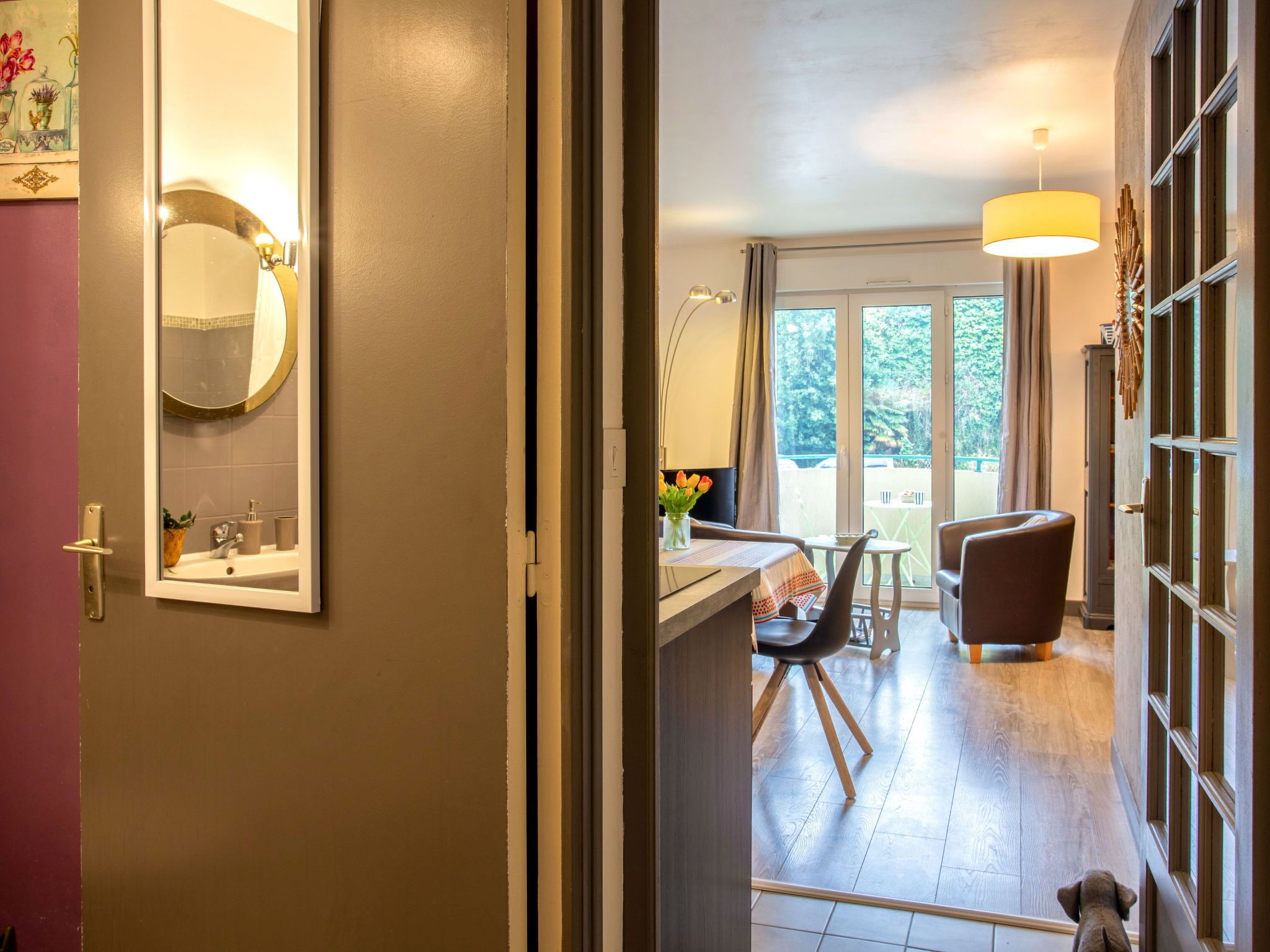 A hotel room with a bathroom, a dining area, and a view of the outdoors.