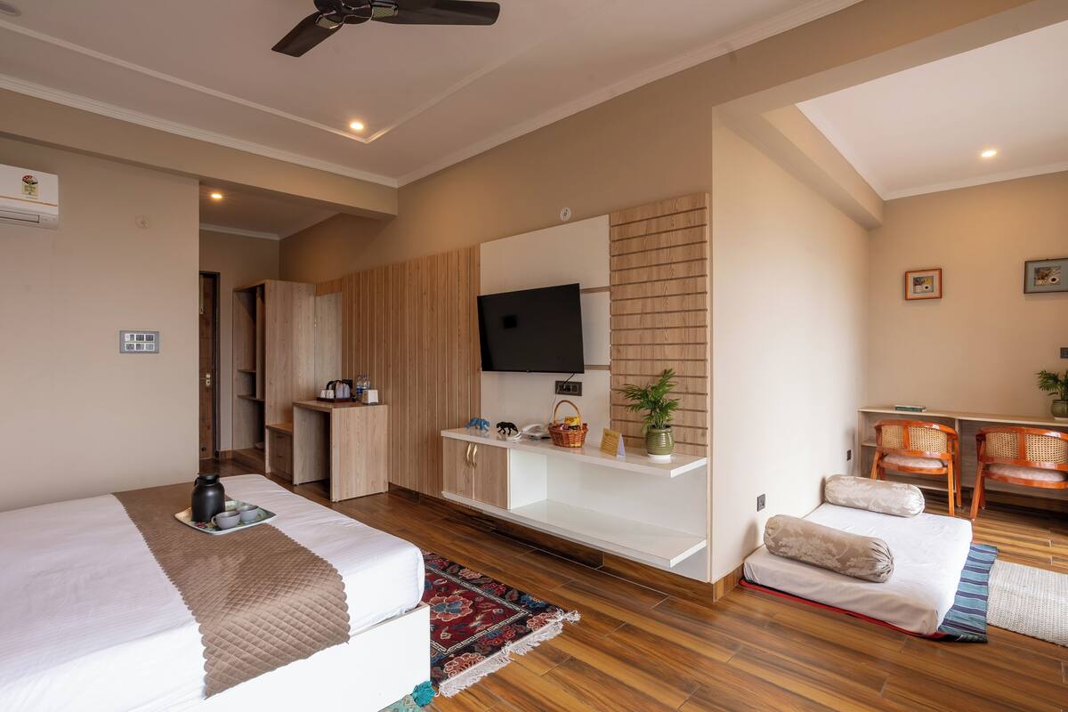 Una habitación de hotel moderna con cama, escritorio, televisor y zona de estar.