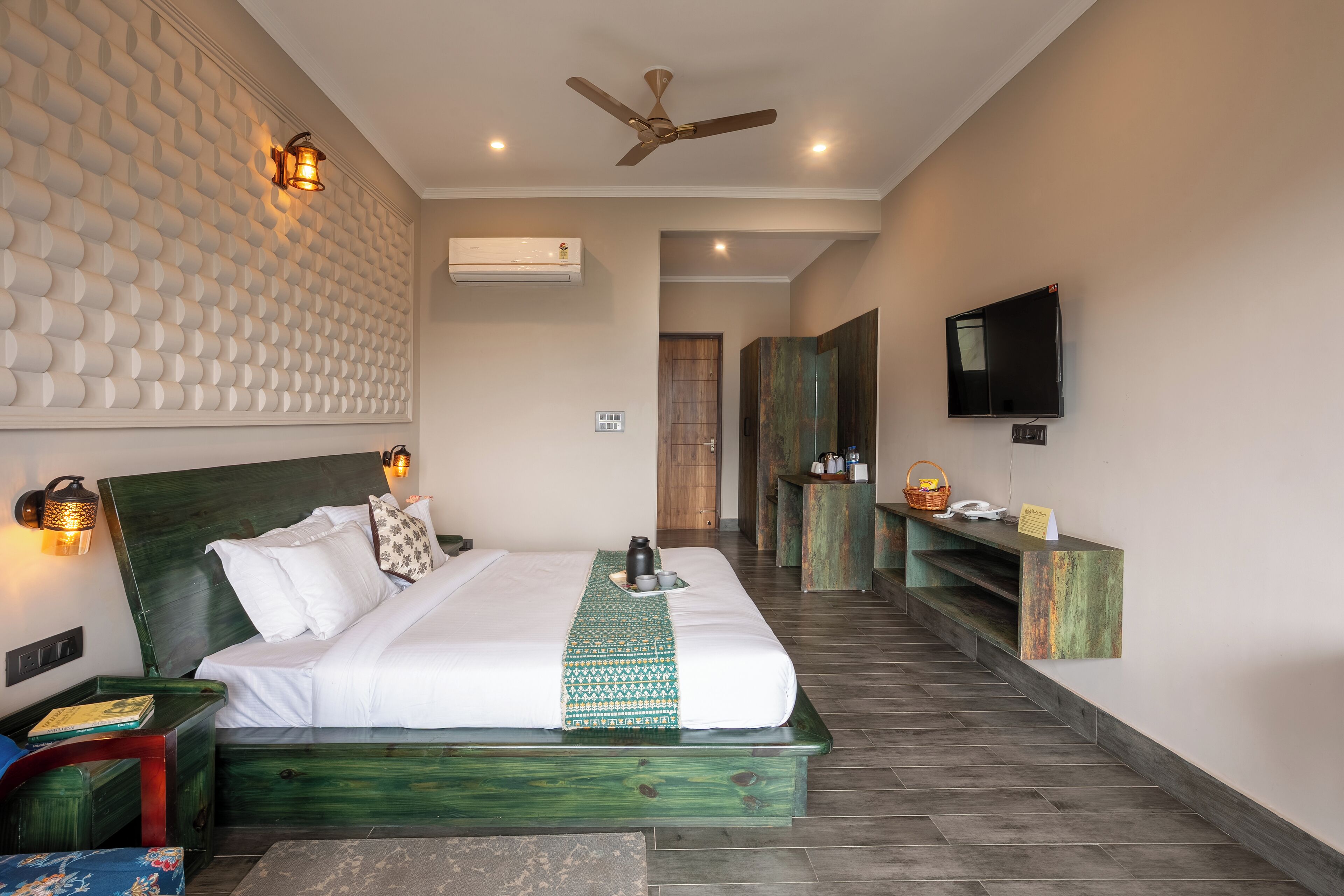 A hotel room with a large bed, a ceiling fan, a TV, and a reception desk.