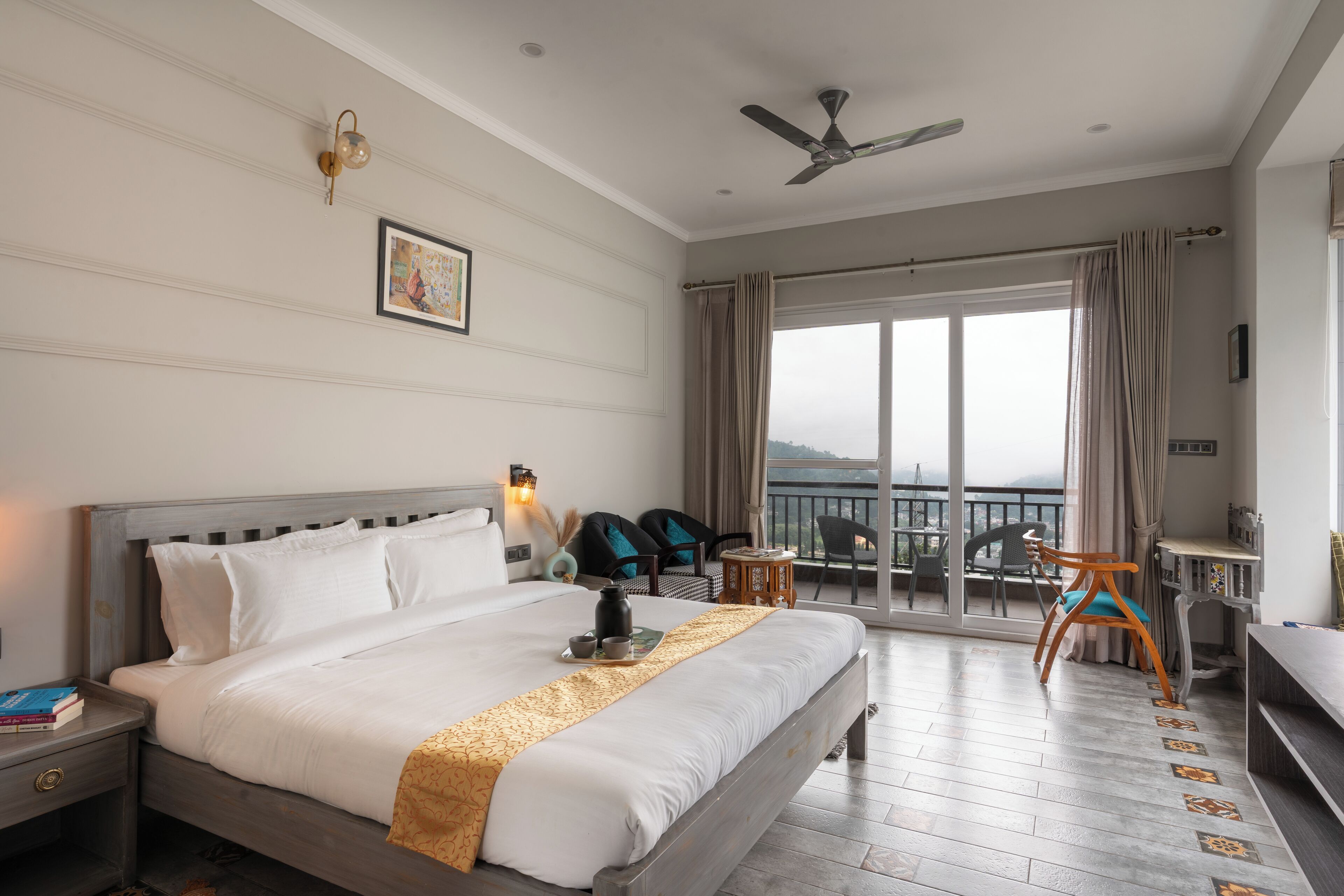 A hotel room with a large bed, a desk, a chair, and a balcony with a view.