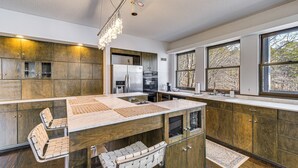 Une cuisine moderne avec des meubles en bois, un îlot central et une grande fenêtre qui laisse entrer la lumière naturelle.