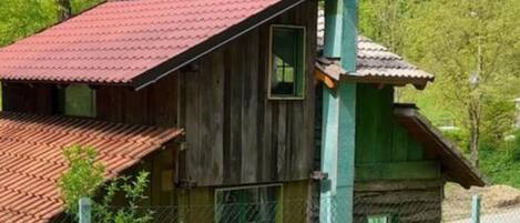 A rustic cabin with a red-tiled roof, wooden walls, and a chimney.