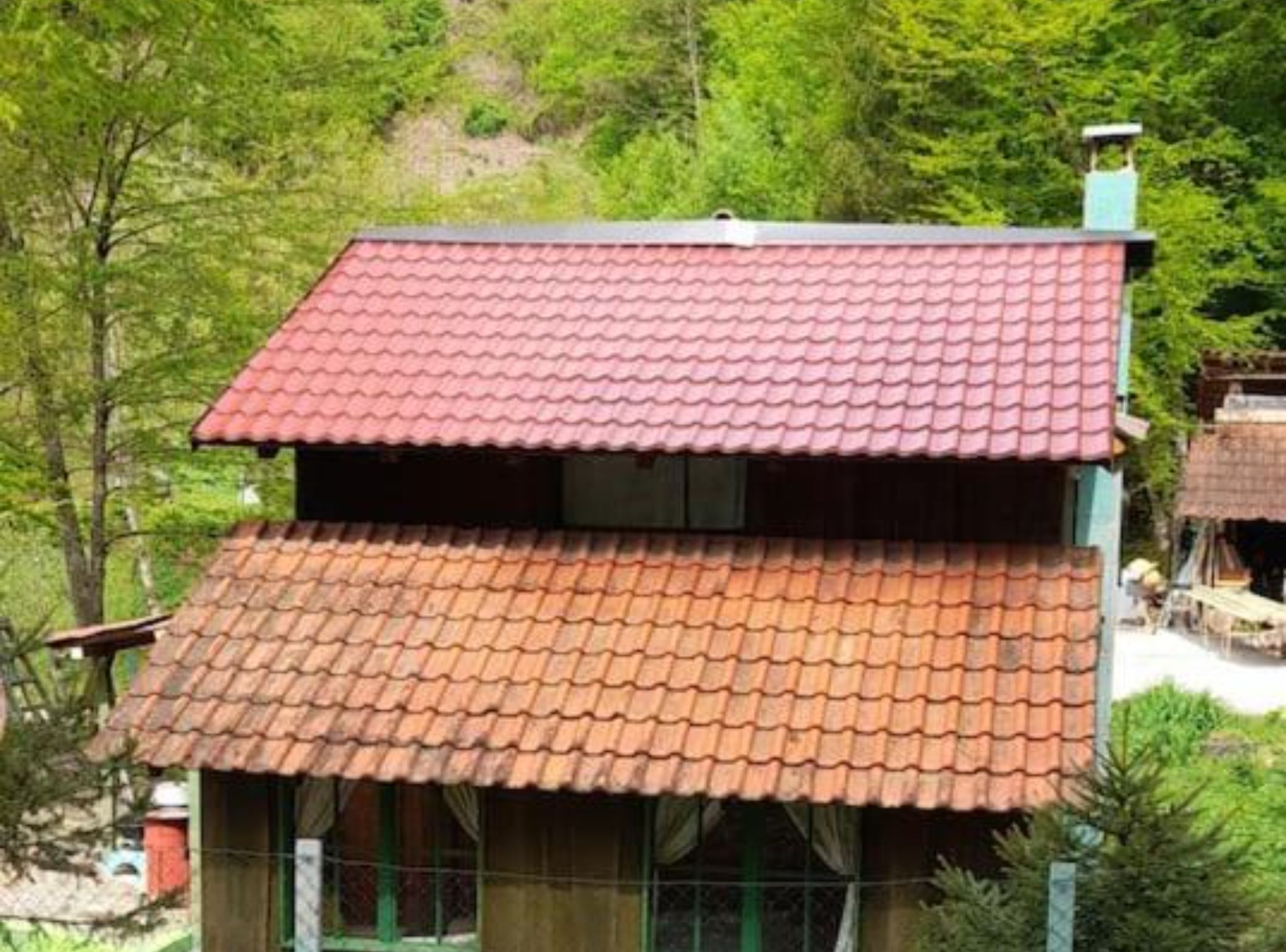 Een gebouw met twee verdiepingen, een rode dakbedekking en een groene gevel.