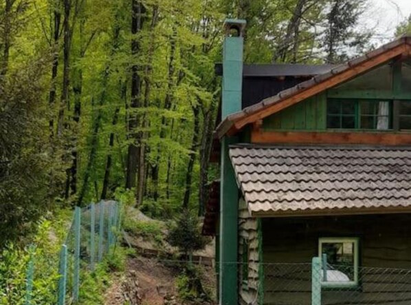 A cabin with a sloped roof, wooden walls, and a window.