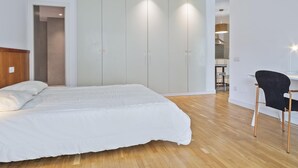 Een moderne slaapkamer met een groot bed, een bureau en een kledingkast.