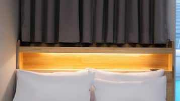 A bed with white bedding, a wooden headboard, and a grey curtain.