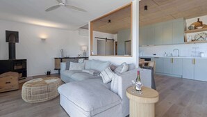 Una sala moderna con un sofá modular, una mesa de centro redonda de madera y un espejo grande.