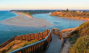 Une zone côtière dotée d’une promenade en bois qui mène à une plage de sable et à une rivière.