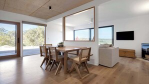 Una sala de estar moderna con una mesa de comedor de madera, sillas, un sofá y un televisor.