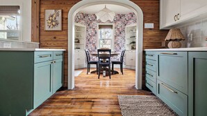 Een keuken met turquoise kastjes, een houten plafond en een eetgedeelte met bloemenbehang.