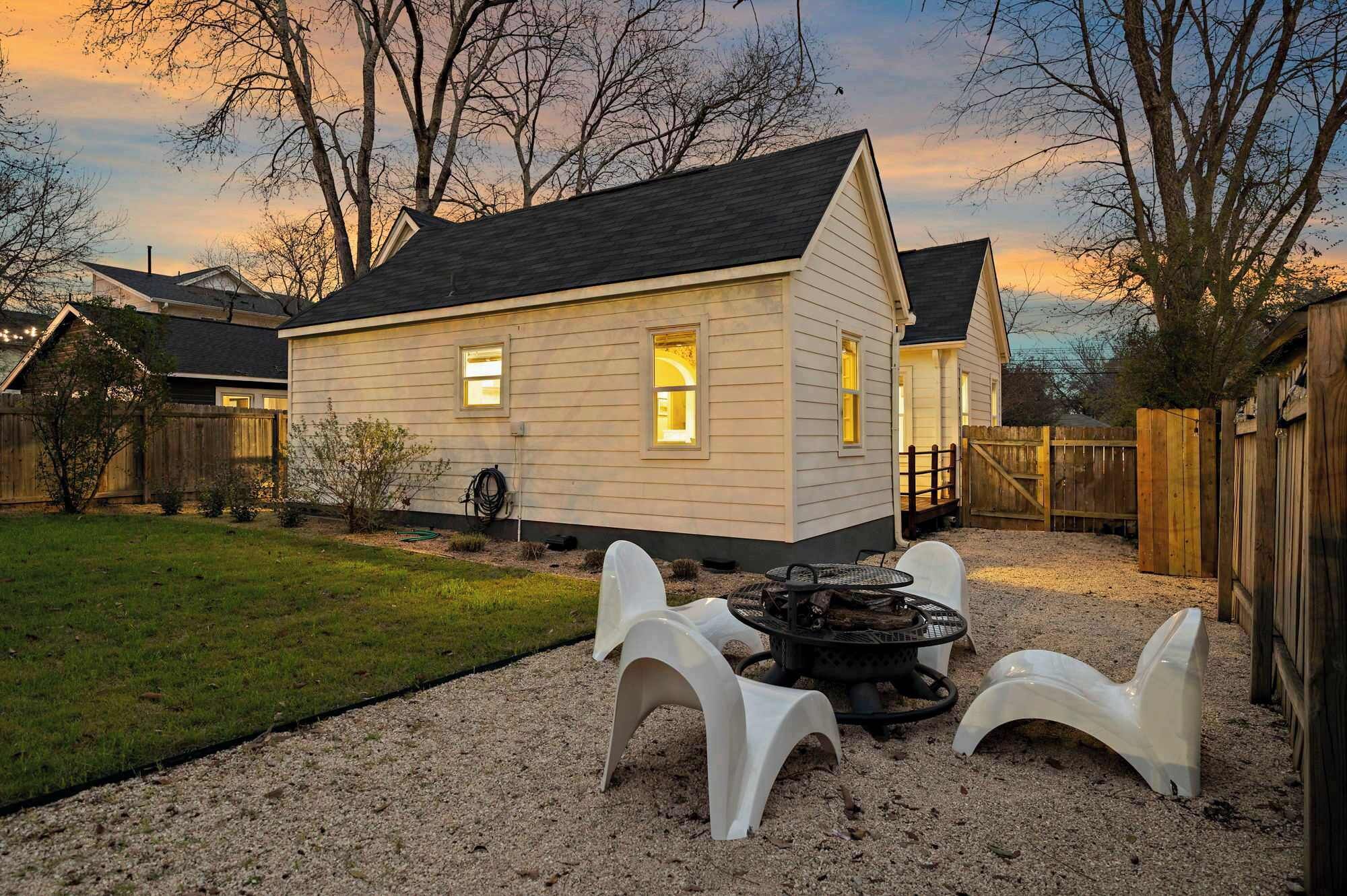 A house with a gravel patio, a fire pit, and a wooden fence.