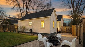 Een huis met een grindpad, een vuurkorf en een houten omheining.