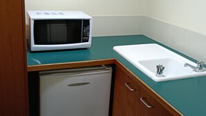 Une petite cuisine équipée d’un four à micro-ondes, d’un évier et d’un petit réfrigérateur.