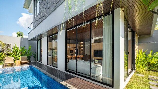 Ein modernes Haus mit Swimmingpool, großen Glasfenstern und einem gepflegten Garten.
