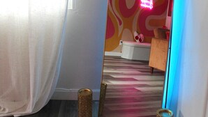 A room with a large mirror reflecting a bathroom with a bathtub and a shower. There are two wicker baskets on the floor.