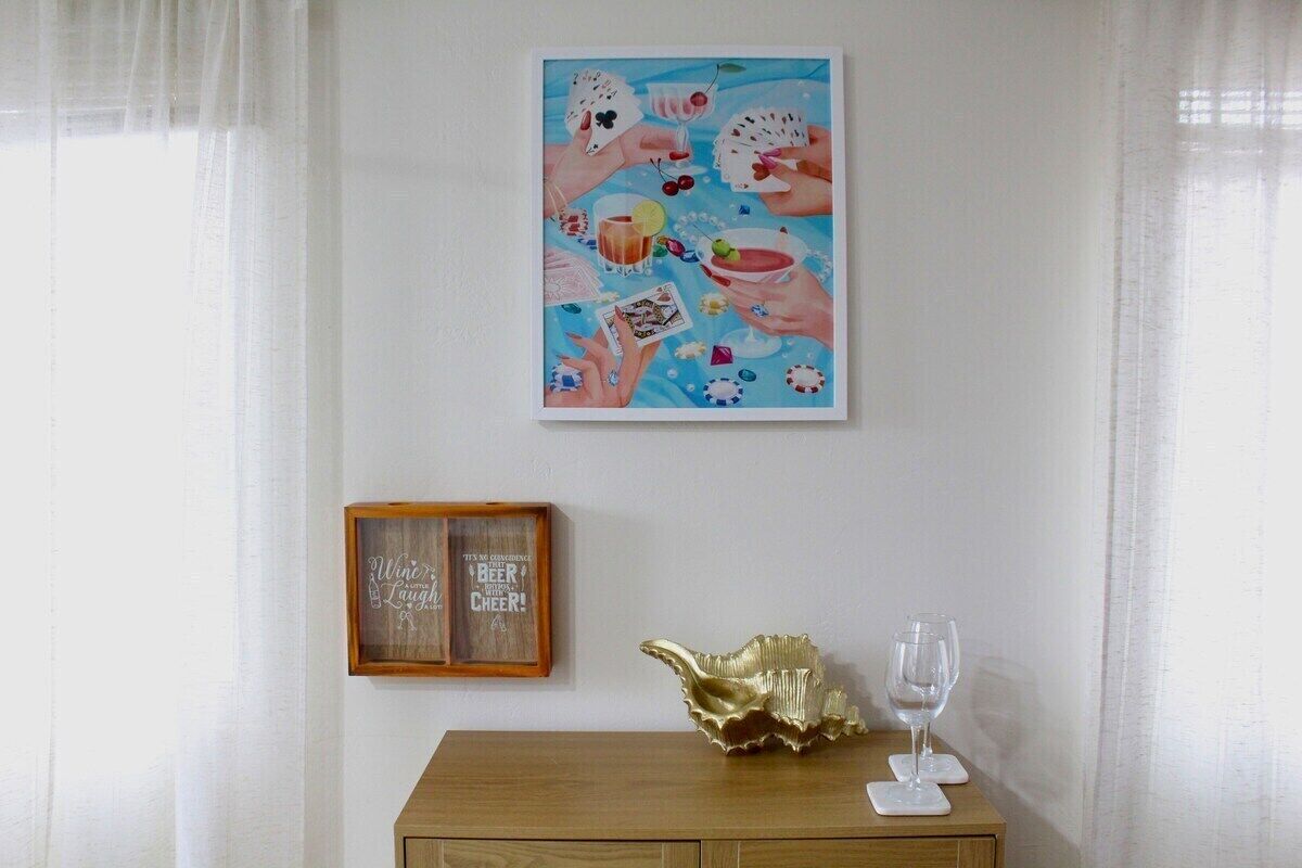 A room with a wooden table, a framed picture, and a glass on the table.