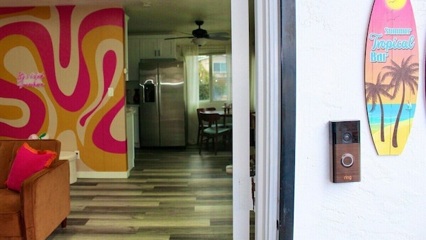 A kitchen with a modern design, a dining area with a table and chairs, and a surfboard decoration on the wall.