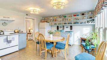 A kitchen with a dining table, chairs, and a refrigerator.