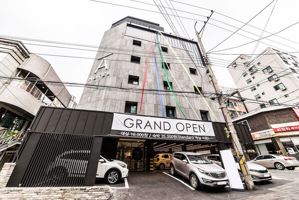 A building with a sign reading "GRAND OPEN" and a large display of cars parked outside. - Hotel A (Seoul)