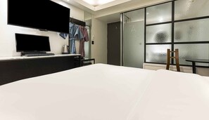A hotel room with a bed, a desk with a television, a coffee maker, and a sliding door with frosted glass. - Hotel A (Seoul)