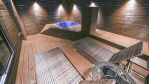 A sauna room with wooden walls, a blue hot tub, and a spiral staircase. - Hotel A (Seoul)