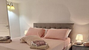 A modern bedroom with a large bed, a nightstand, and a wall-mounted lamp.