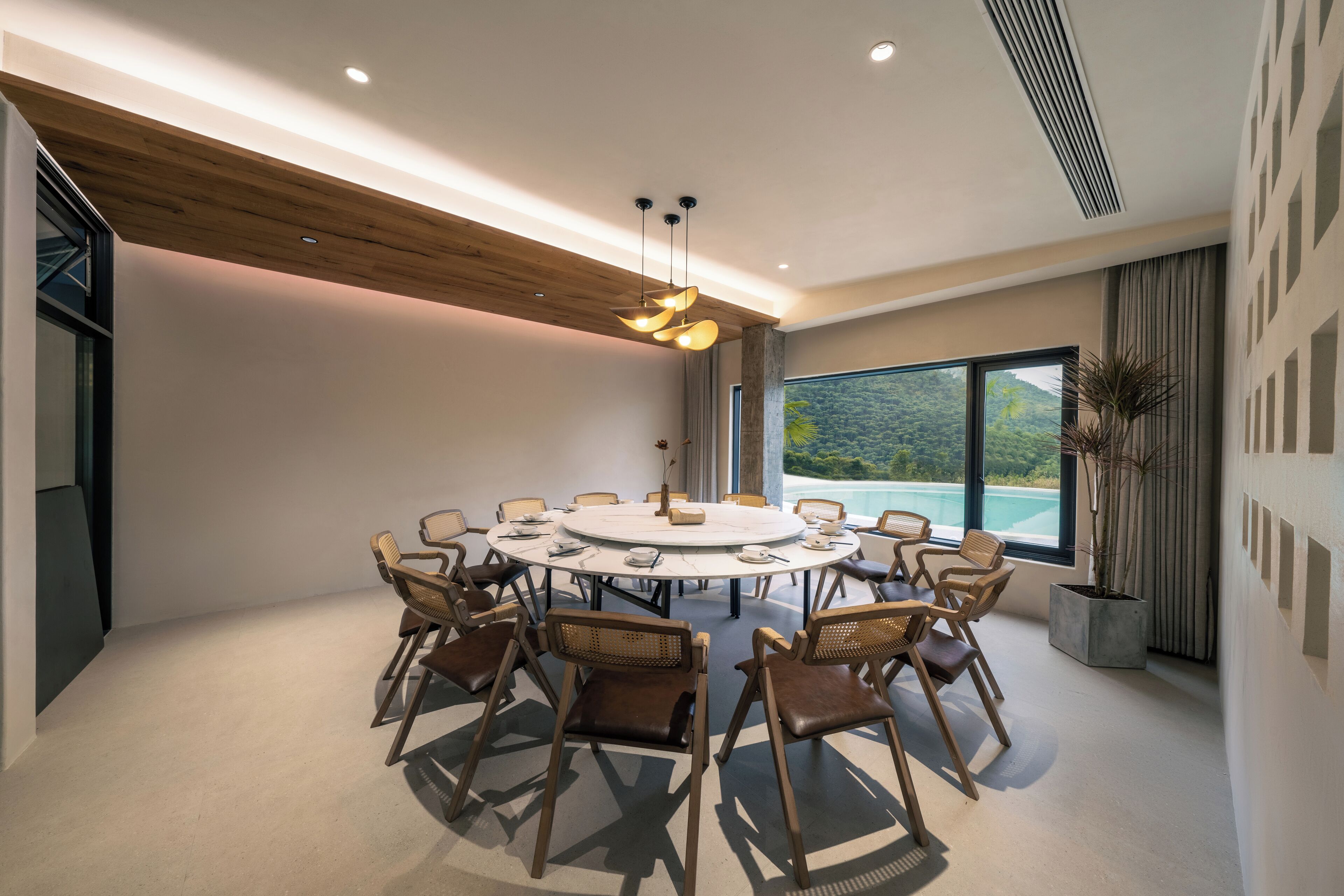 A modern conference room with a round table, comfortable chairs, and a large window offering a view of the outdoors.